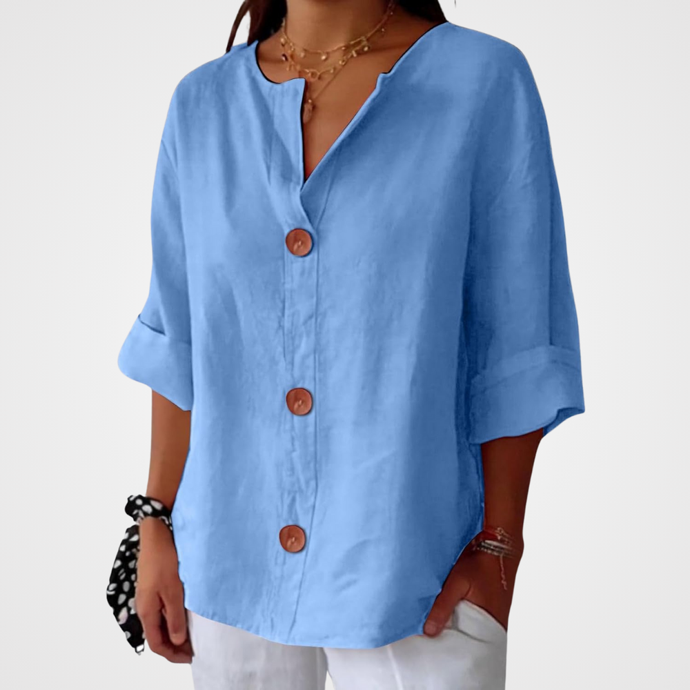 Blue linen V-neck blouse with three-quarter rolled sleeves and large wooden buttons in a relaxed, loose-fitting style.