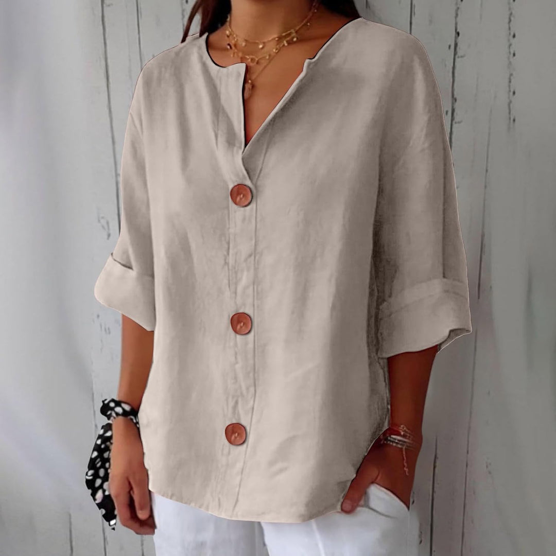 Beige linen V-neck blouse with three-quarter rolled sleeves and large wooden buttons in a relaxed, loose fit.