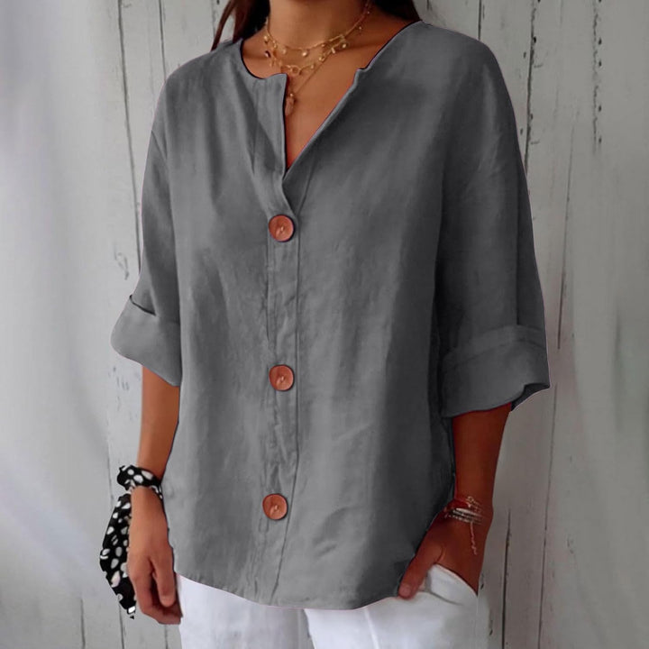 Grey linen V-neck blouse with three-quarter rolled sleeves and statement wooden buttons in a relaxed, loose fit.