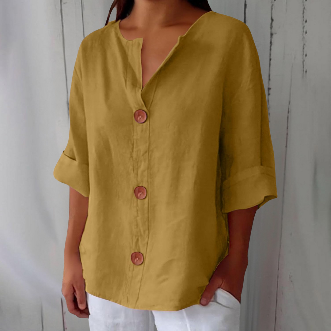 Mustard yellow linen V-neck blouse with wooden buttons and rolled three-quarter sleeves.
