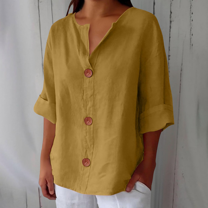 Mustard yellow linen V-neck blouse with wooden buttons and rolled three-quarter sleeves.