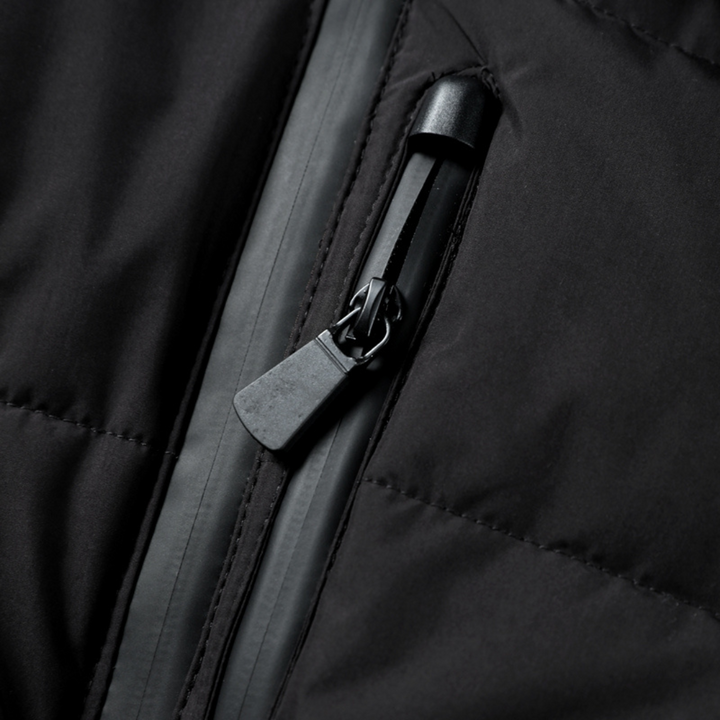 Close-up of a black quilted puffer jacket featuring a secure, sealed zip pocket with a matte black pull tab.