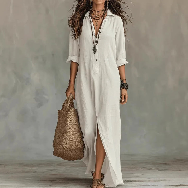 White linen-look maxi shirt dress with a collared neckline, half-button front, and side slit, styled with a woven bag.