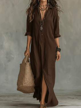Woman wearing a brown linen maxi shirt dress with a collared neckline, button-front, and side slit, styled with a tote.