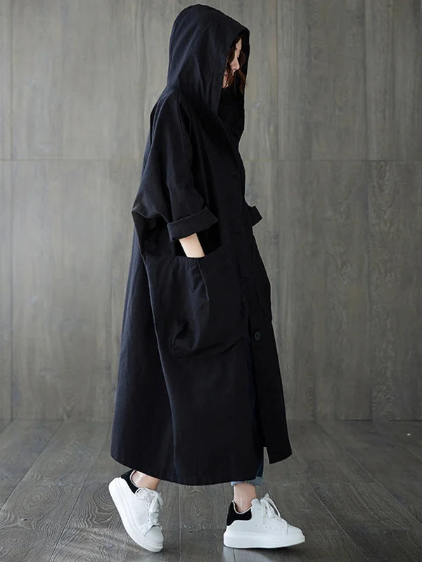 Woman wearing a black longline hooded coat with an oversized fit and large front patch pockets.