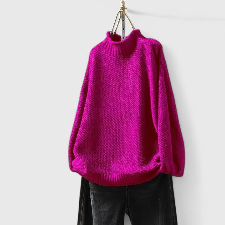 Bright magenta mock neck knitted jumper with a textured finish, dropped shoulders, and ribbed trim, paired with black jeans.