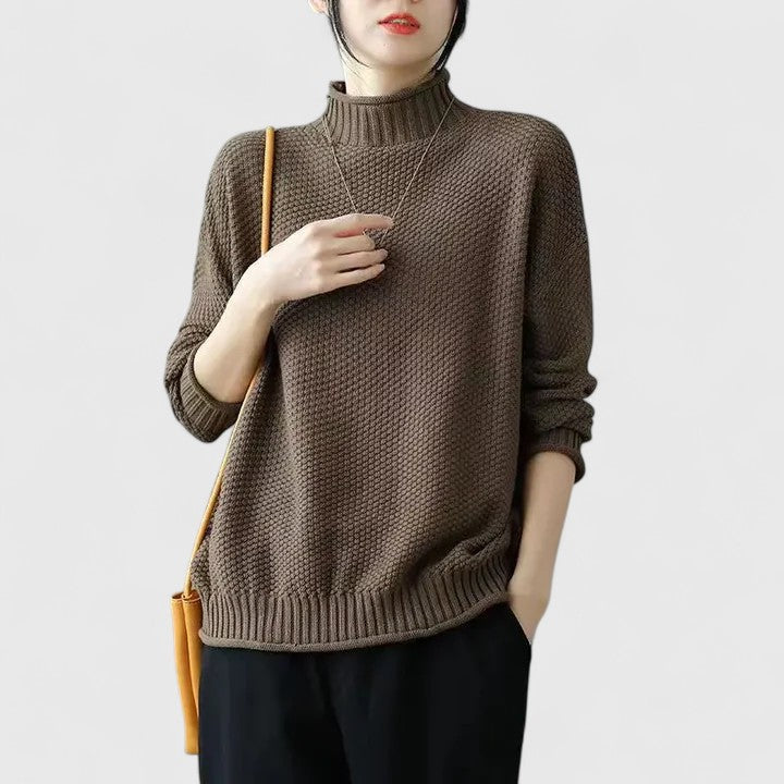 Brown textured knitted jumper with a mock neckline, dropped shoulders, and ribbed hem, worn with black trousers.