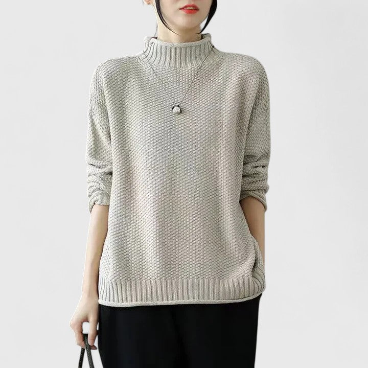 Beige mock neck jumper in a textured knit with dropped shoulders and ribbed hem and cuffs.