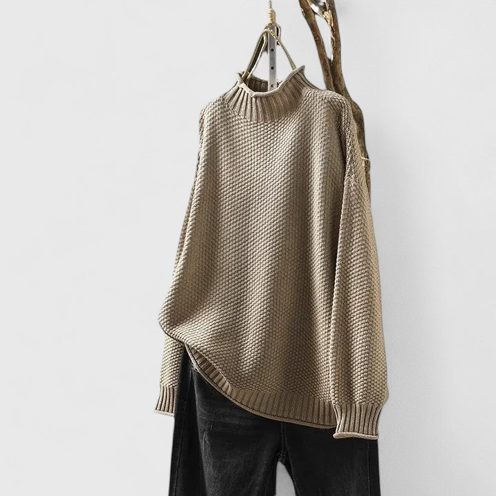 Beige textured mock neck knitted jumper with dropped shoulders and ribbed hem, styled with black trousers.