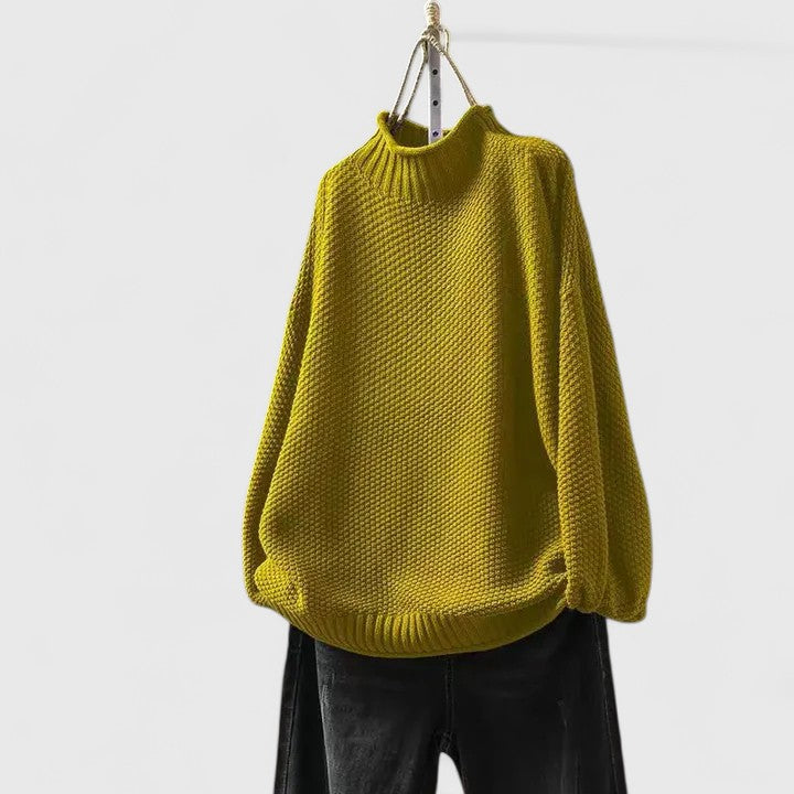 Mustard yellow mock neck jumper in a textured knit with dropped shoulders and ribbed hem, hanging above black jeans.