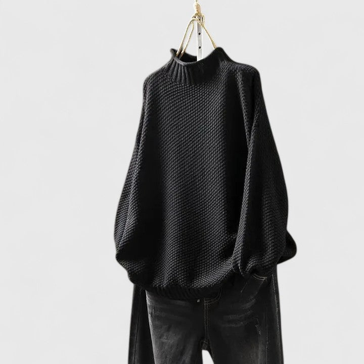 Black textured knit jumper with a mock neckline, dropped shoulders, and ribbed cuffs hanging against a white background.