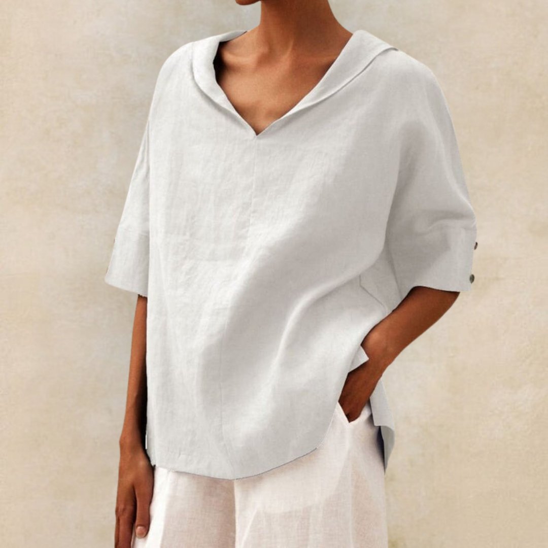White linen-look V-neck blouse with a draped collar, relaxed fit, and half-length sleeves with button cuff details.