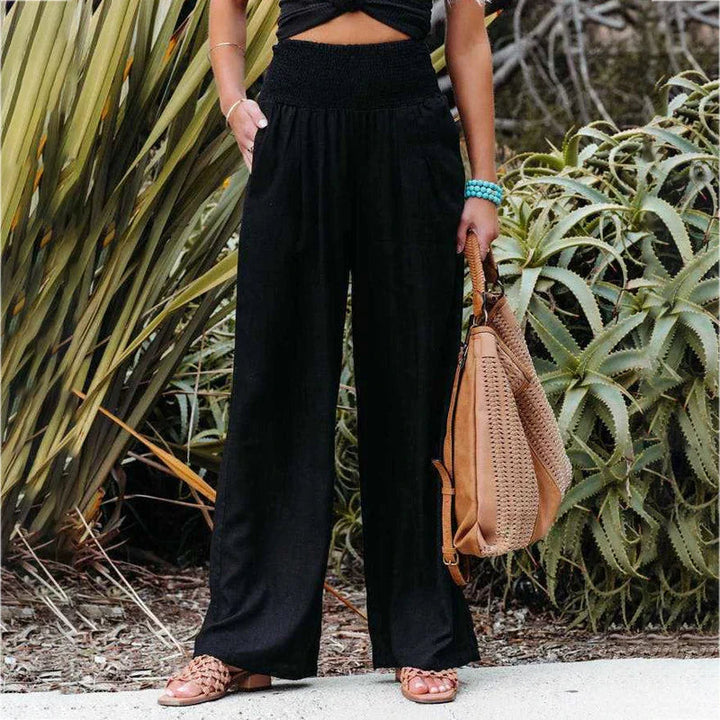 Iris black linen summer trousers with a relaxed fit, elastic waistband, and flowing fabric.
