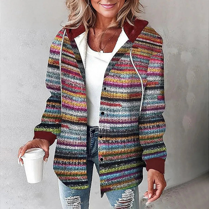 Woman wearing a cozy, multi-colored striped hooded jacket with a button-front closure and dark red trim.