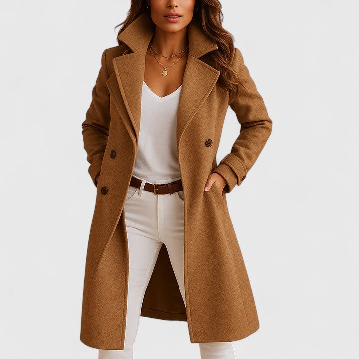Camel brown longline tailored coat with notched lapels, button front, and side pockets worn over white trousers.