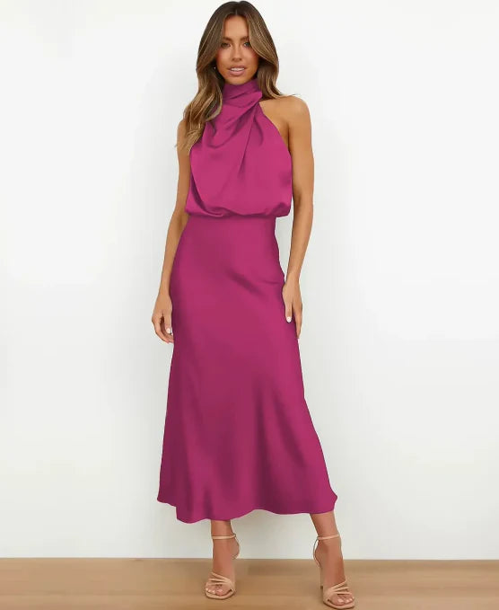 Magenta satin halter maxi dress with a draped blouson bodice and floor-length skirt, worn with nude strappy heels.