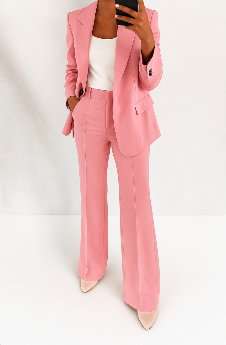 Woman wearing a dusty pink tailored suit with a single-button blazer and straight-leg trousers with a center crease.