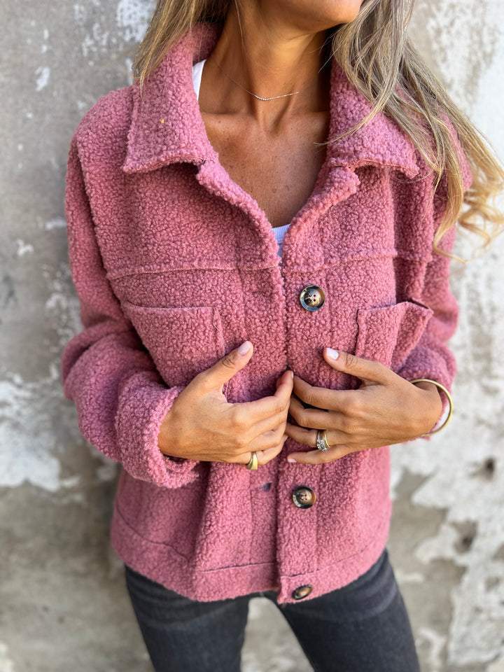 Dusty pink teddy jacket with a button-up front, spread collar, and chest pockets in a relaxed, plush fabric fit.