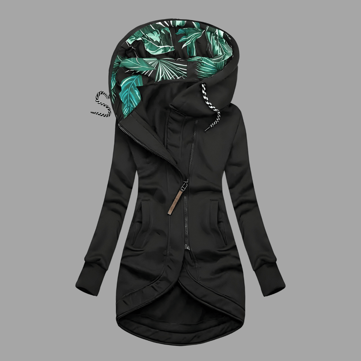 Black longline hooded parka with an asymmetric zip, front pockets, and a green tropical-print hood lining.