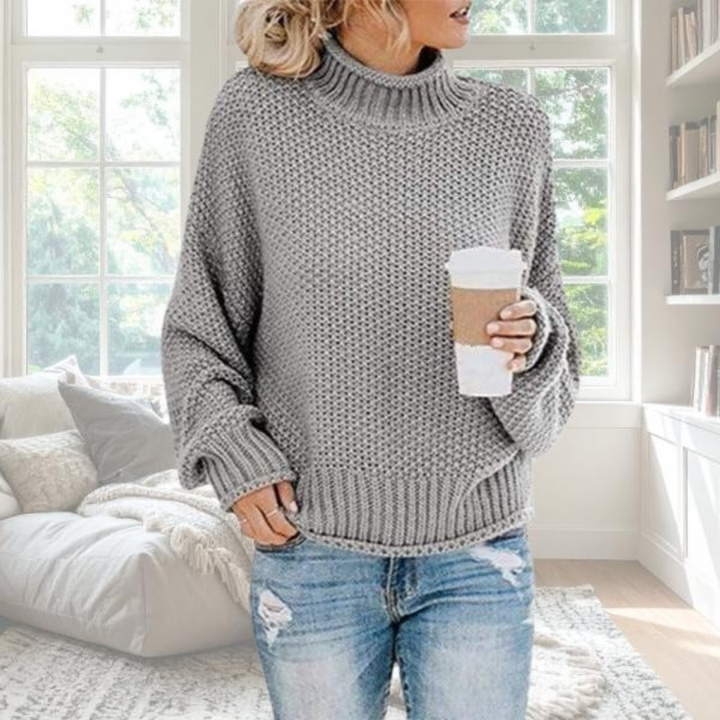 Grey chunky knit turtleneck jumper with a relaxed fit, dropped sleeves, and ribbed trim, styled with blue jeans.