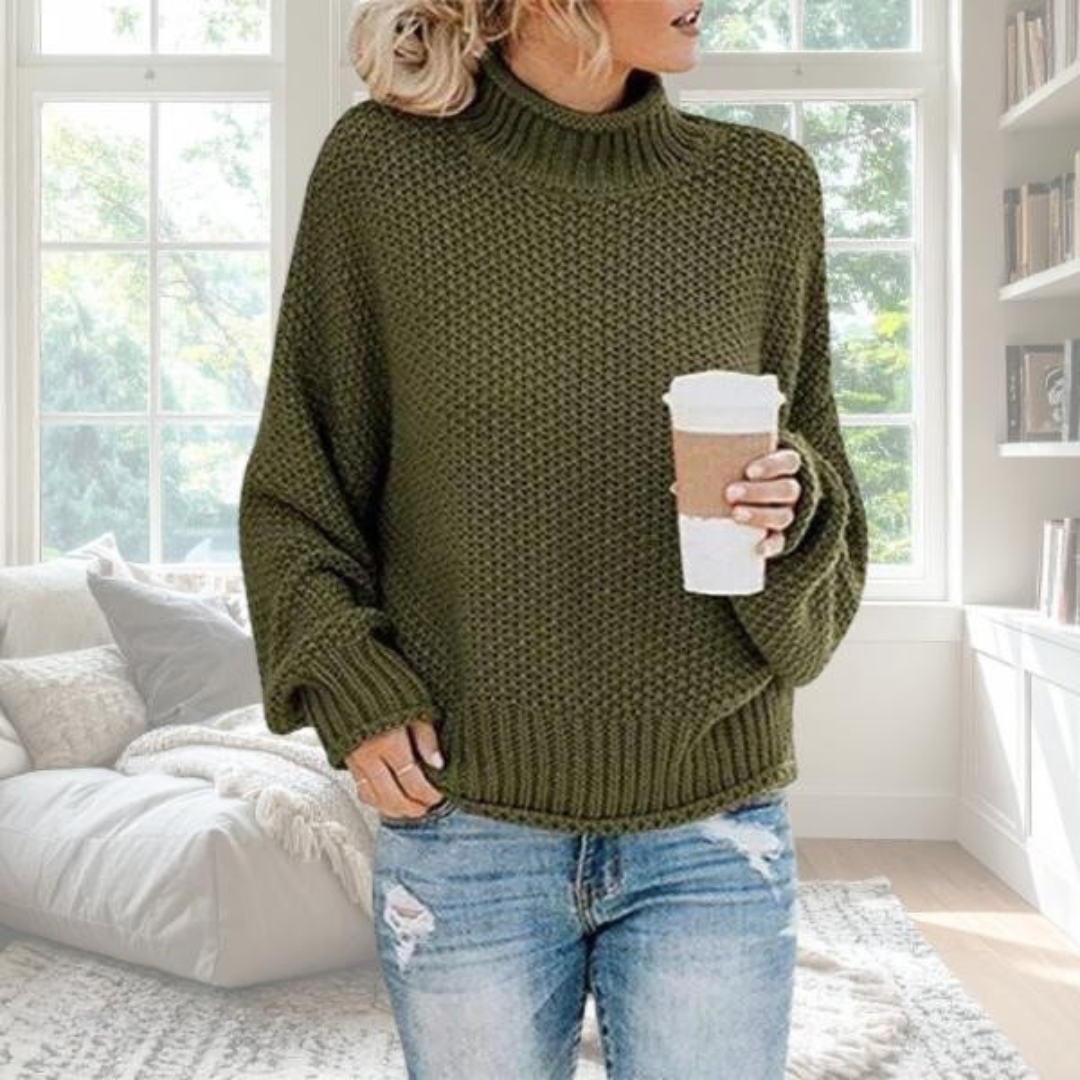 Olive green chunky knit turtleneck jumper with dropped sleeves, ribbed trim, and a relaxed fit worn with blue jeans.