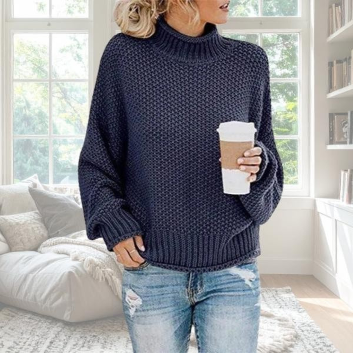 Navy blue chunky knit turtleneck jumper with a relaxed fit, dropped sleeves, and ribbed trim, styled with jeans.
