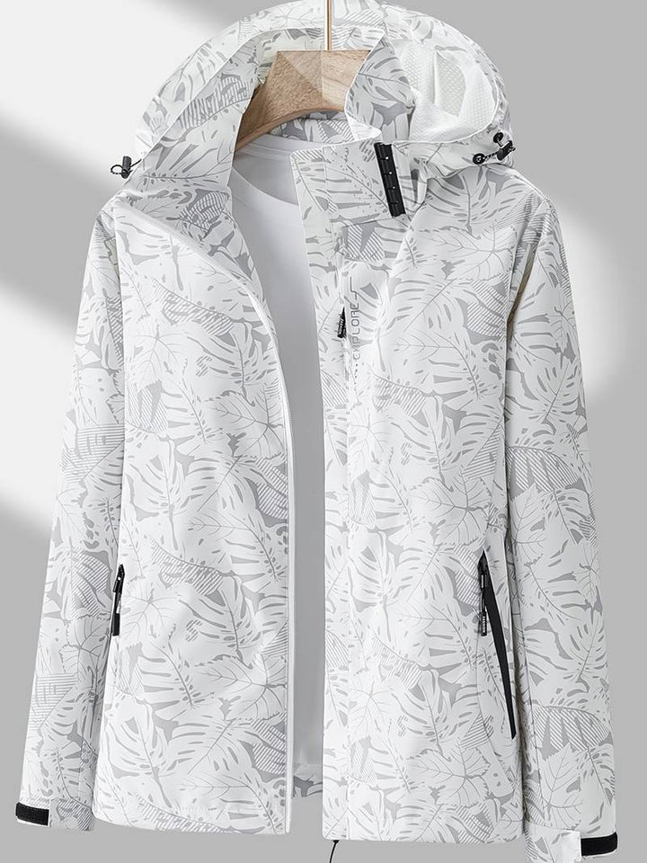 White waterproof hooded jacket featuring a grey tropical leaf print, full-length zip, and adjustable hood.