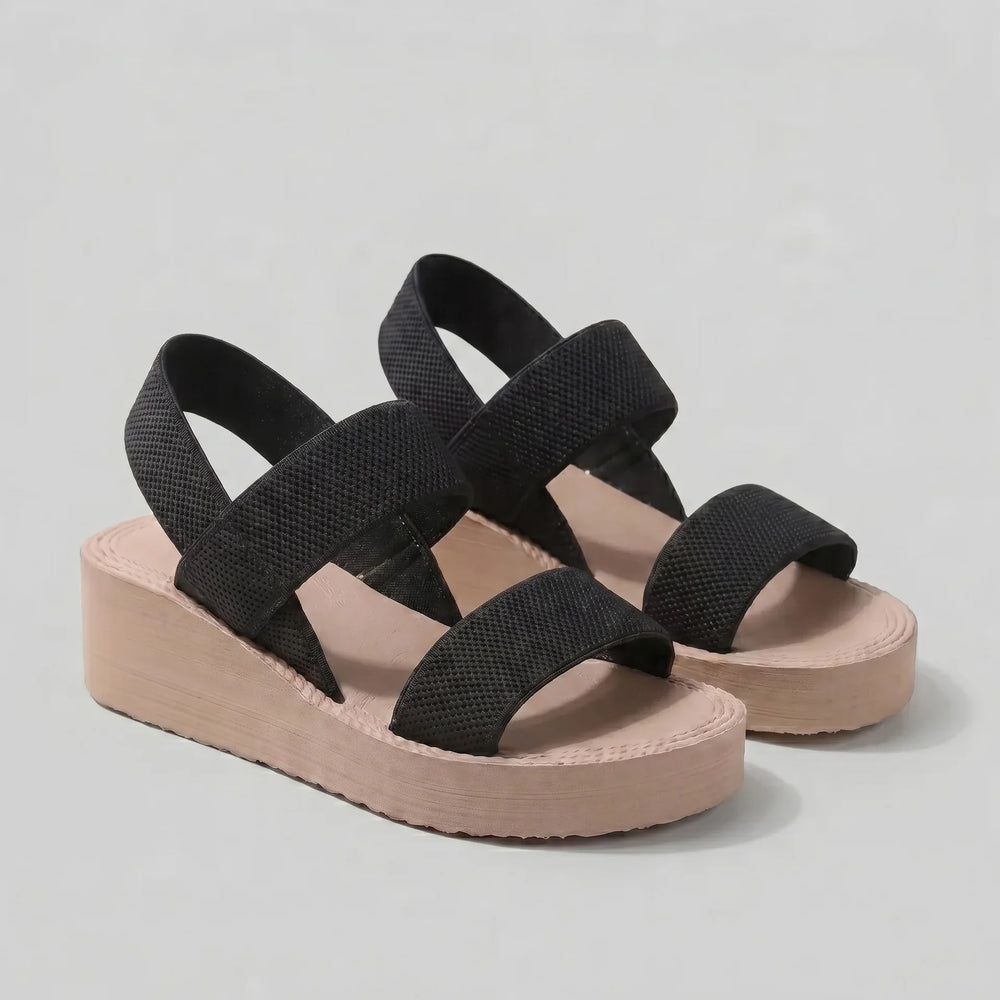 Black sandals with pink platforms on a gray background