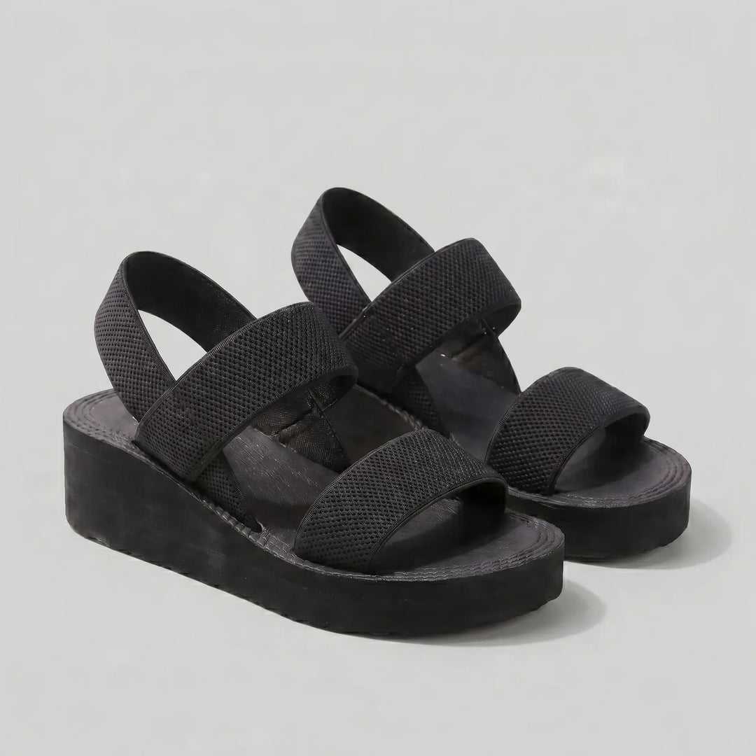 Black sandals with multiple straps on a light gray background