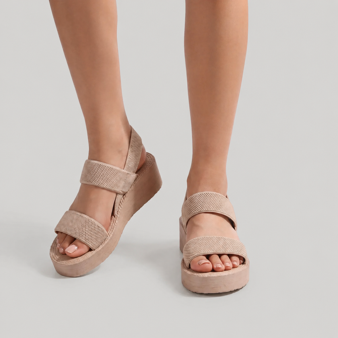 Beige sandals worn by a person on a light gray background