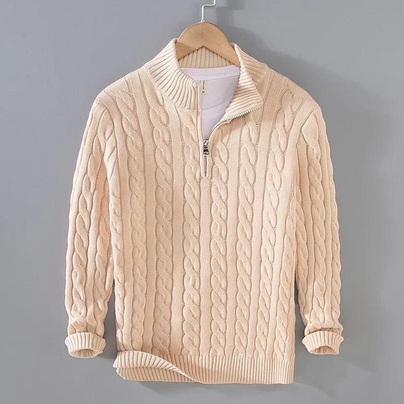 Beige cable-knit men's jumper featuring a half-zip funnel neck, ribbed cuffs, and hem, hanging on a wooden hanger.