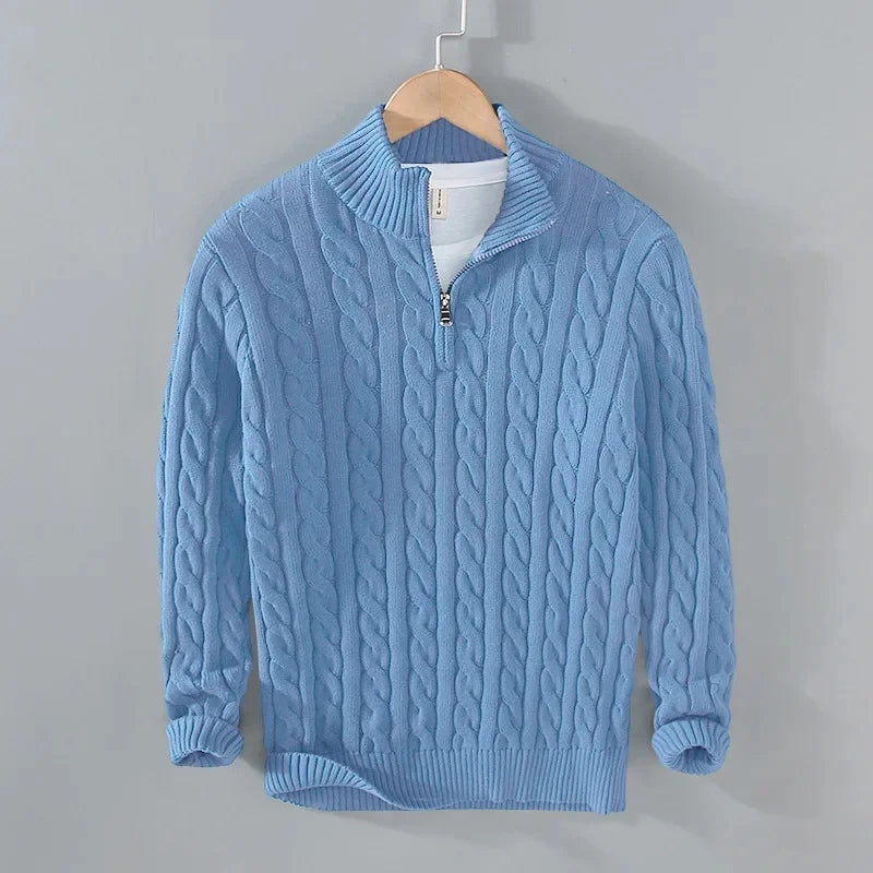 Light blue cable-knit men's jumper with a half-zip funnel neck, ribbed cuffs, and hem, hanging on a wooden hanger.
