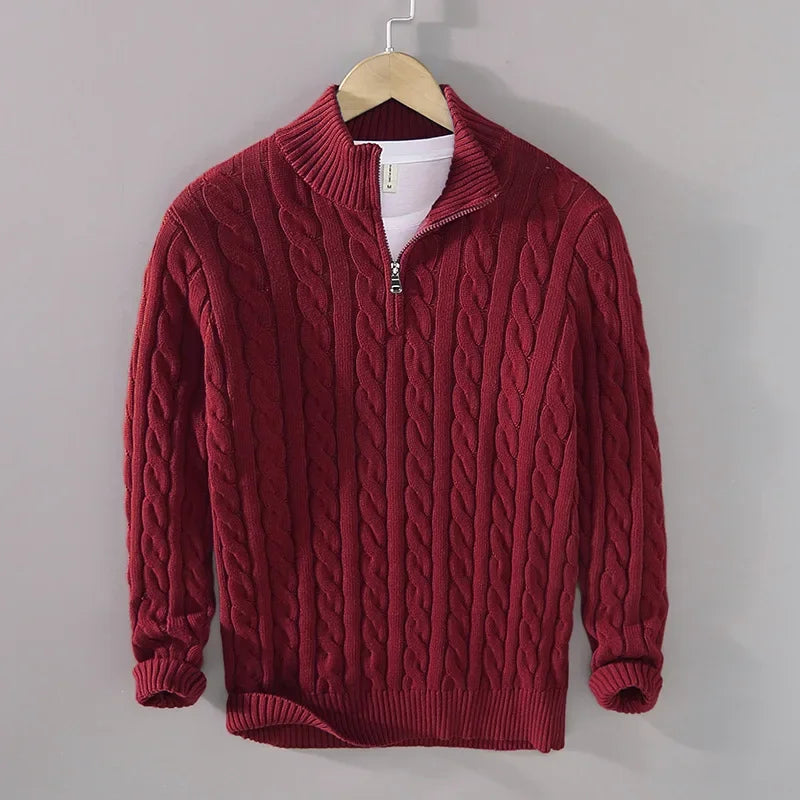 Deep red men's cable-knit jumper featuring a half-zip funnel neck, ribbed cuffs, and hem, hanging on a hanger.