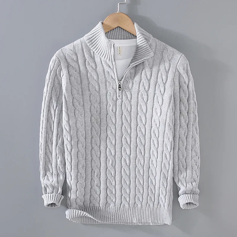 Light grey cable-knit men's jumper featuring a half-zip funnel neck, ribbed cuffs, and hem, hanging on a wooden hanger.