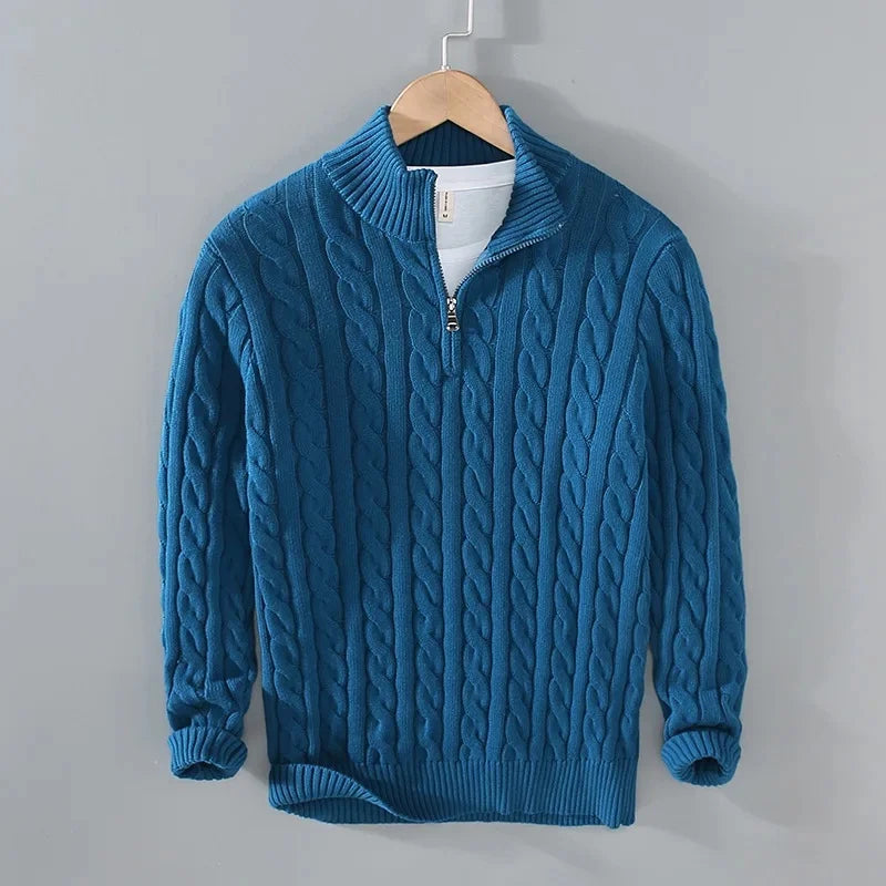 Blue cable-knit men's jumper with a half-zip funnel neck, ribbed cuffs, and hem, hanging on a wooden hanger.