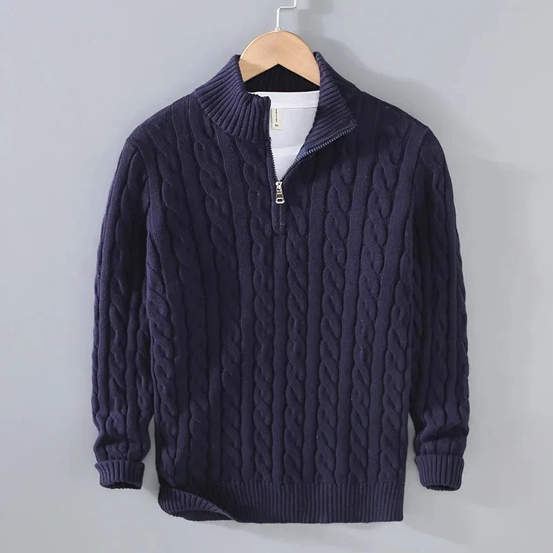 Navy blue cable-knit men's jumper featuring a half-zip funnel neck, ribbed cuffs, and hem, hanging on a wooden hanger.