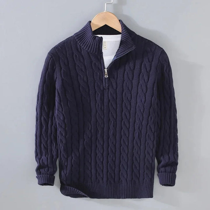 Navy blue cable-knit men's jumper featuring a half-zip funnel neck, ribbed cuffs, and hem, hanging on a wooden hanger.