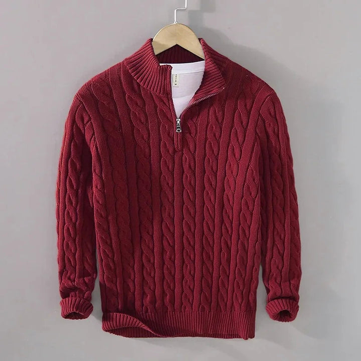 Men's burgundy cable-knit half-zip jumper with a ribbed funnel collar, cuffs, and hem, hanging on a wooden hanger.