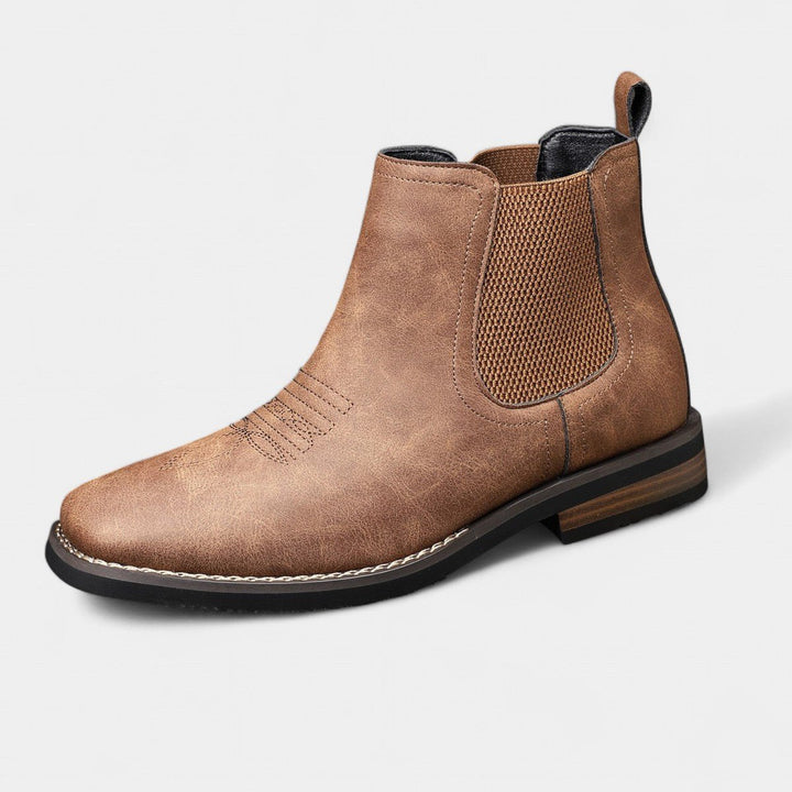 Distressed tan faux leather Chelsea boot with elastic side gussets, western toe stitching, and a stacked block heel.