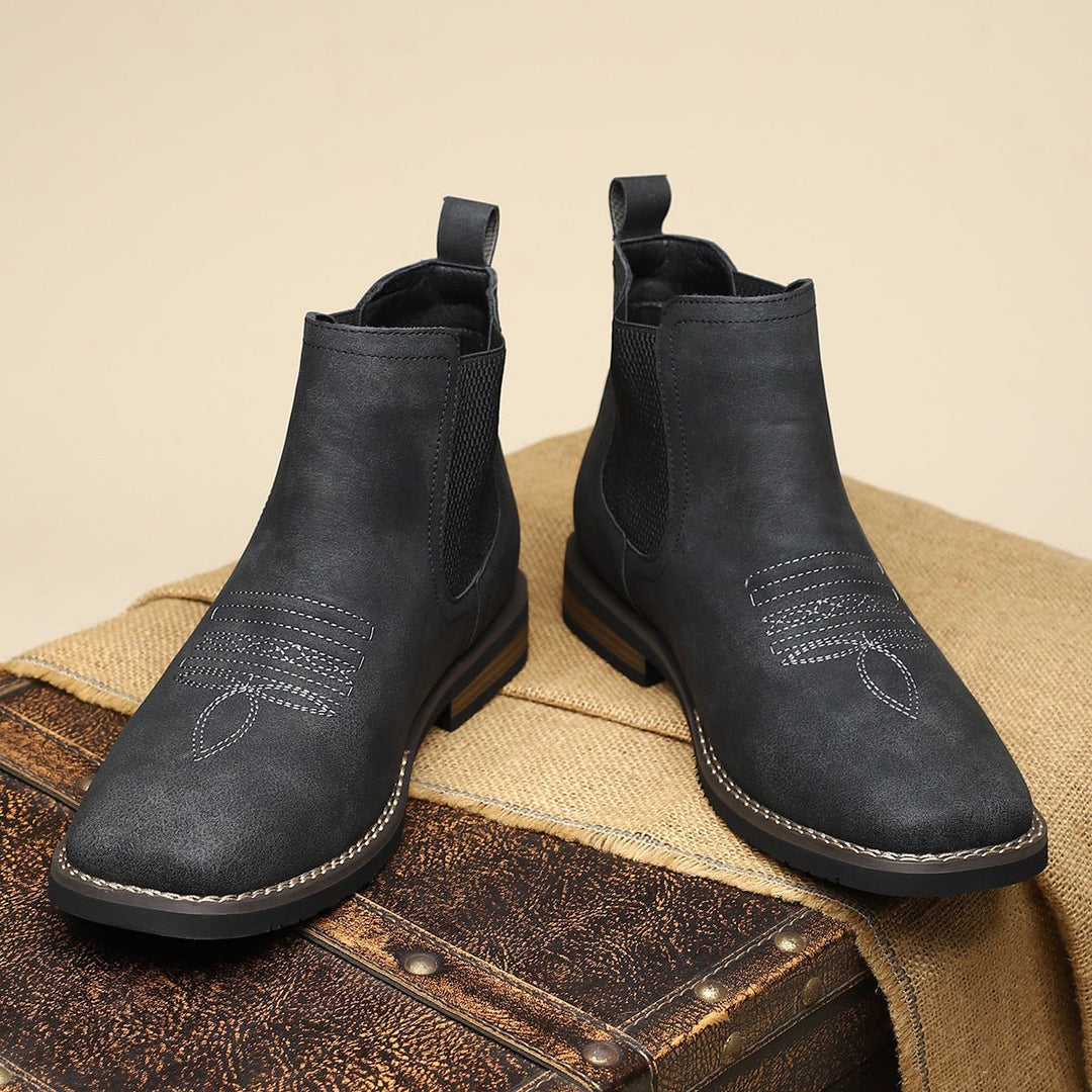 Black distressed faux leather Western Chelsea boots with elastic side panels, pull tabs, and decorative toe stitching.