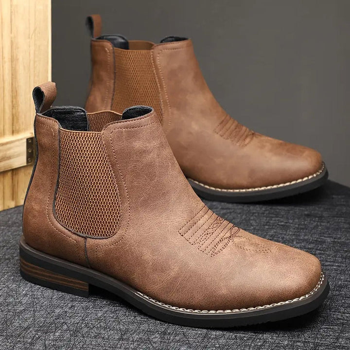 Distressed brown faux leather Chelsea boots with elastic side panels, western toe stitching, and a stacked block heel.