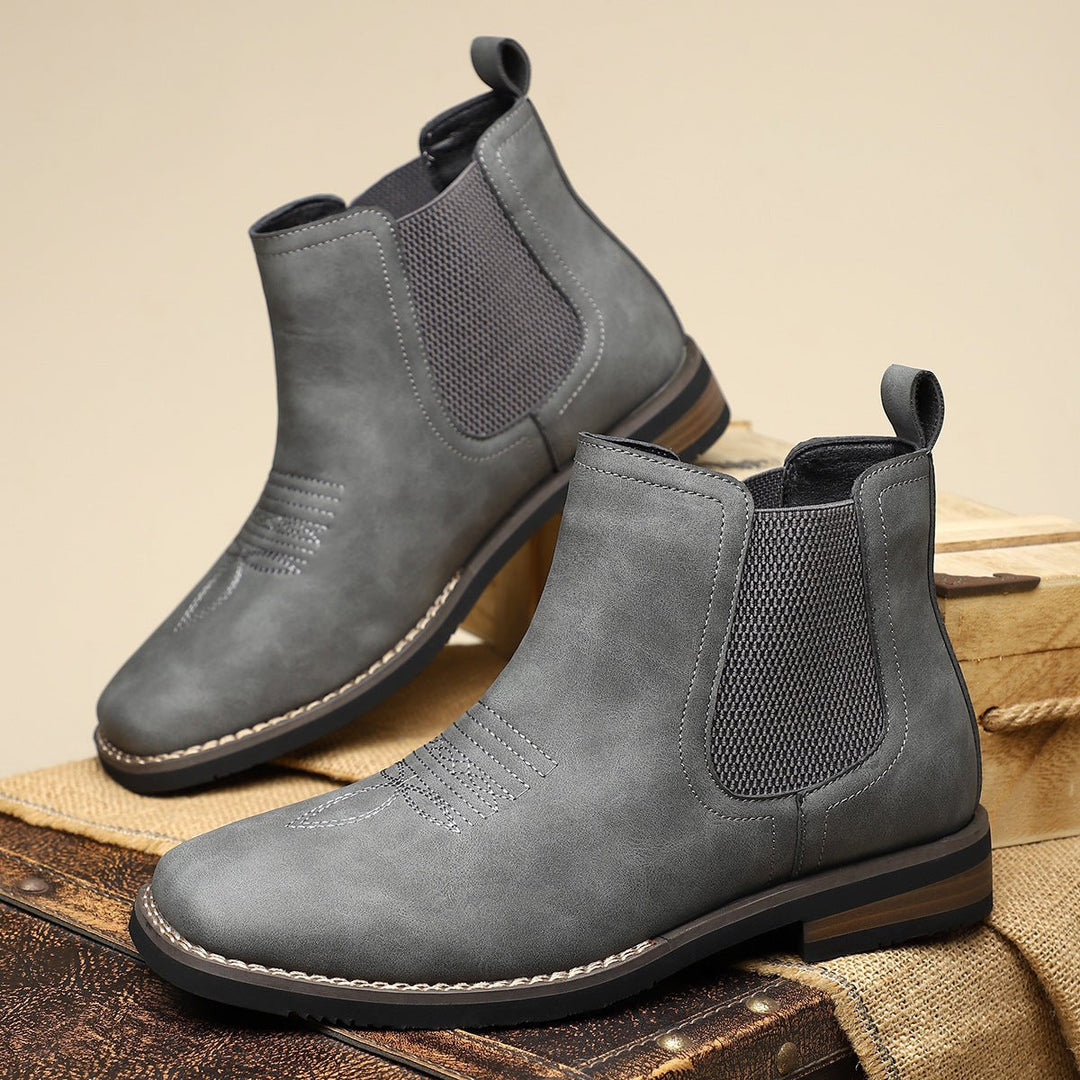 Grey distressed faux leather Chelsea boots with western toe stitching, elastic side panels, and a stacked block heel.