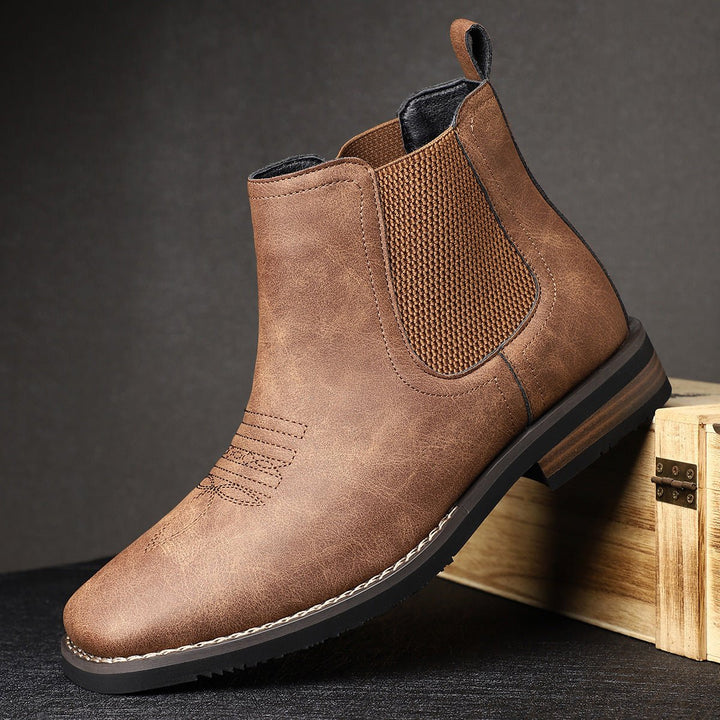 Distressed brown faux leather Chelsea boots with western toe stitching, elastic side panels, and a stacked block heel.