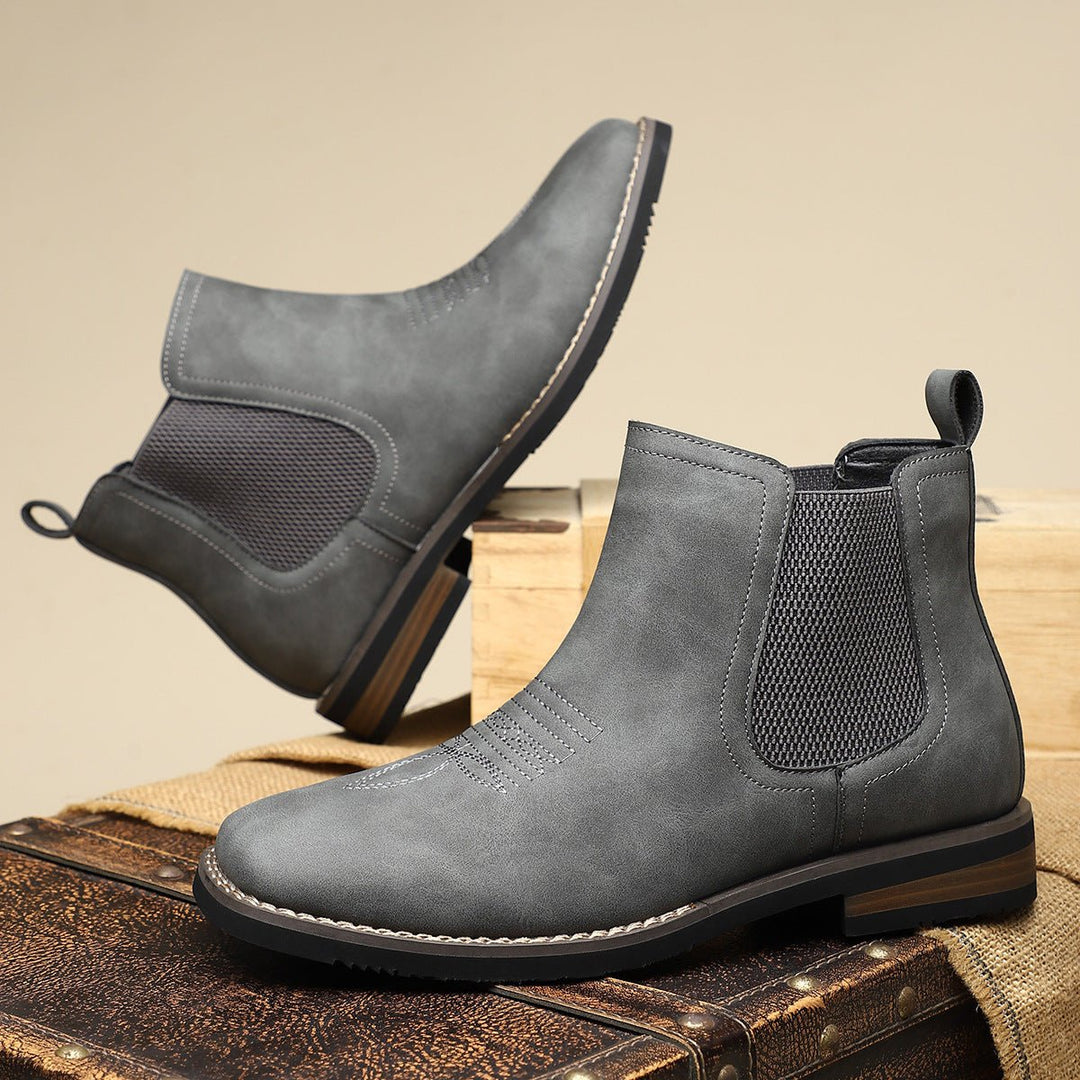 Grey distressed faux leather men's Chelsea boots with western toe stitching, elastic side panels, and a stacked block heel.