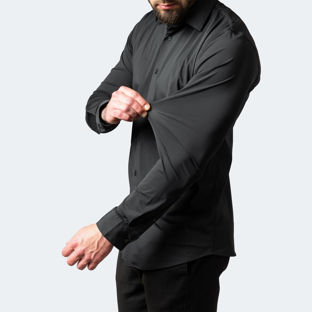 Man wearing a black slim-fit stretch dress shirt, demonstrating the flexible, high-stretch fabric on the sleeve.