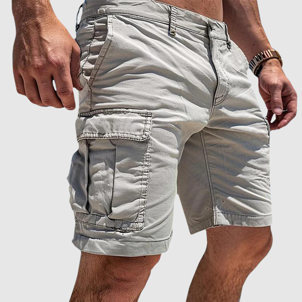 Beige knee-length cargo shorts in soft washed cotton with side flap pockets and a relaxed athletic fit.