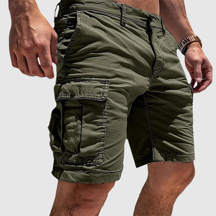 Olive green knee-length cargo shorts in soft washed cotton with large flap-top side pockets and a relaxed athletic fit.
