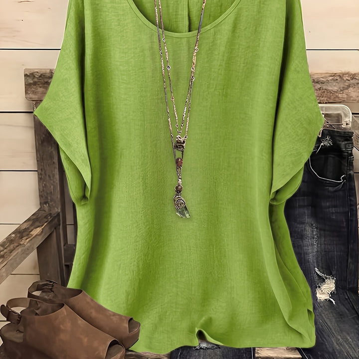 Bright green linen-look top with a round neck and relaxed batwing sleeves, styled with a pendant necklace.