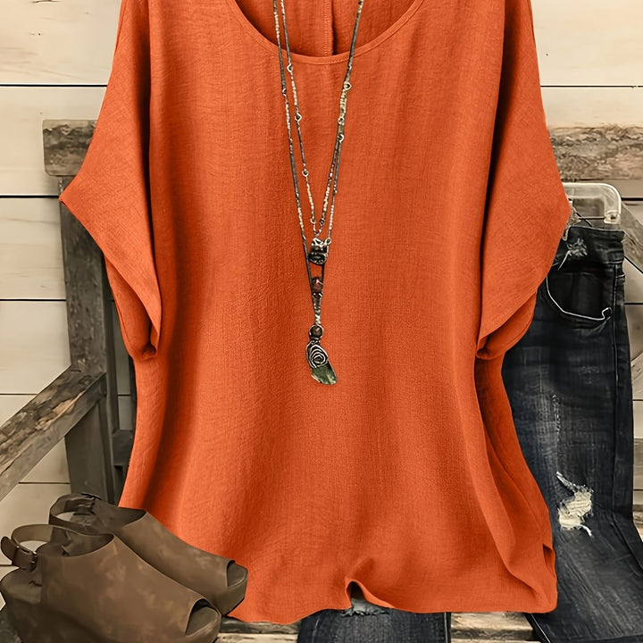 Rust orange linen-look round neck top with batwing sleeves and a layered pendant necklace.