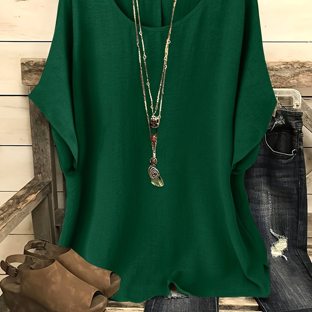 Dark green linen-look top with a round neck and relaxed batwing sleeves, styled with a layered necklace.